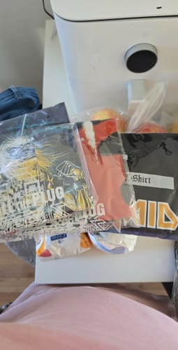 Customer's delivered items, including multiple t-shirts, shown still in their plastic packaging.
