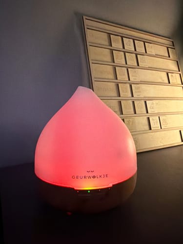 Klant toont de Unity 2.0 diffuser, die aanstaat en een sfeervol roze licht geeft.