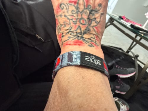 A customer wearing the patterned Trust Your Path Bracelet on their tattooed wrist.