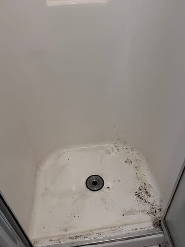 Reviewer's dirty shower floor with heavy soap scum buildup before cleaning with the Bathroom Concentrate.