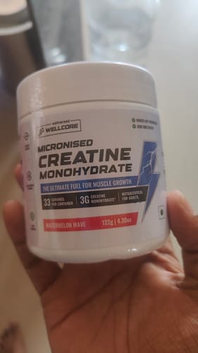 Reviewer holding the white tub of Wellcore Creatine Monohydrate in Watermelon Wave flavor.