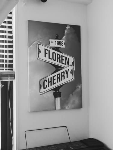 Customer's oversized personalized street sign canvas with the names 'Floren' and 'Cherry' and 'Est. 1998' on a wall.