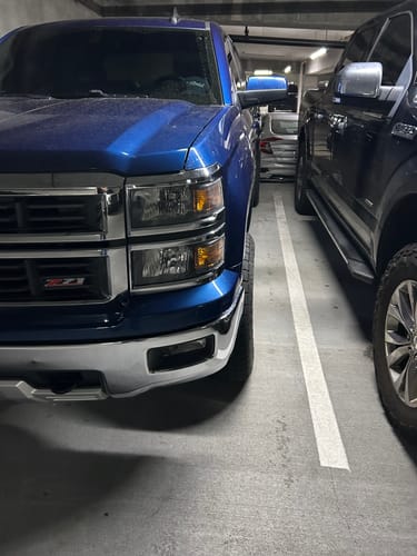 Customer's blue Silverado with a wider stance from 1.5" wheel spacers in a parking garage.