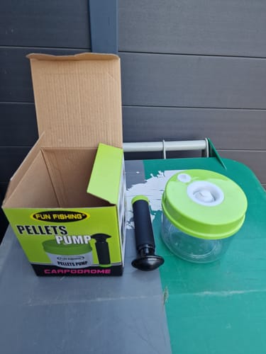 Klant toont de Fun Fishing Pelletpomp met de container en de pomp uit de doos gehaald op een groene tafel.