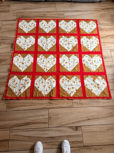 Customer's homemade snuggle quilt with a heart pattern, using the Angel Wings Polycotton Fabric for the red binding.