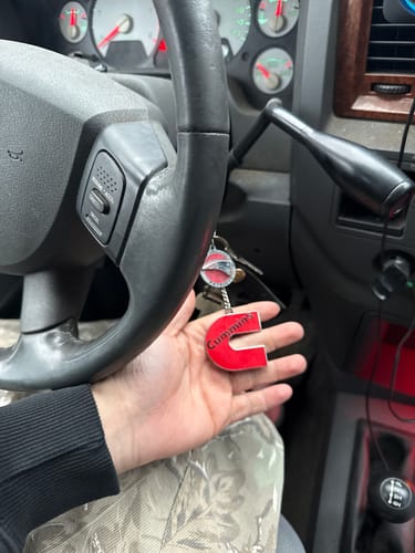 Customer holds the red C-shaped Cummins Keychain in their hand inside a vehicle.