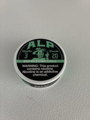Customer's can of ALP Refreshing Chill Nicotine Pouches on a white textured surface.
