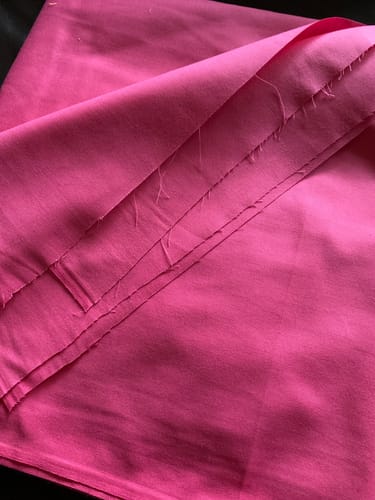 Customer's vibrant pink Plain Polycotton Fabric, folded in several layers.