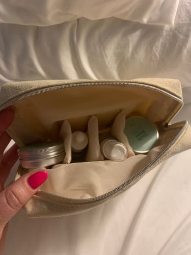Customer holding open the travel bag for the Mini 5-Step Clear Skin Kit, showing the organized skincare products inside.