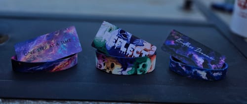 Reviewer's three straps from the Non-Interactive Mystery 3-Pack displayed with their collector cards on a dark surface.