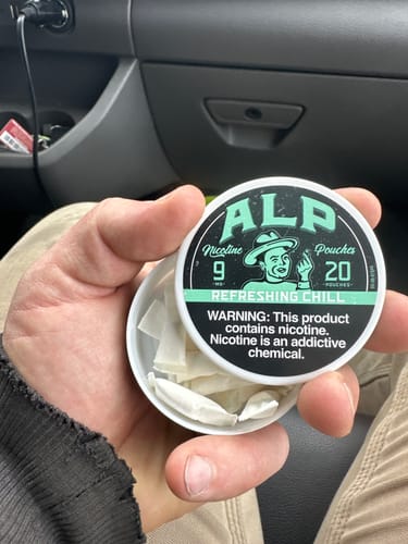Customer holding an open tin of Refreshing Chill Nicotine Pouches, showing the white pouches inside.