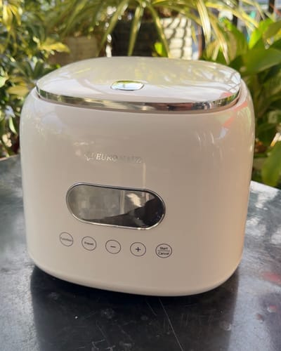 A reviewer's modern, off-white Eurohauz Healthy Rice Cooker sitting on an outdoor table.