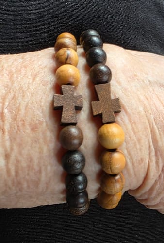 Close-up of a customer wearing the two Remain With Me Lent Bracelets, each with a wooden cross.