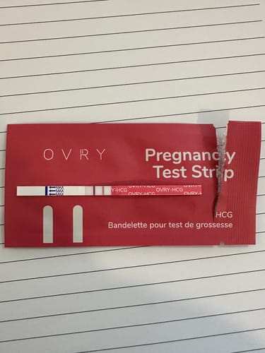 Customer's Ovry Pregnancy Test Strip showing a clear positive result with two lines on its packaging.