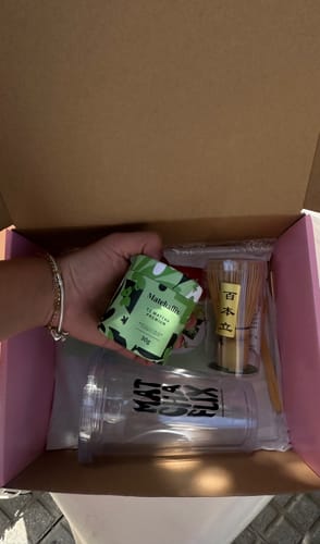 Una clienta muestra la lata de té del Pack Experiencia Iniciación sobre la caja abierta con los accesorios.