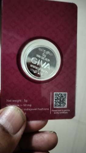 Customer holding a GIVA 5g silver coin in its burgundy packaging card.
