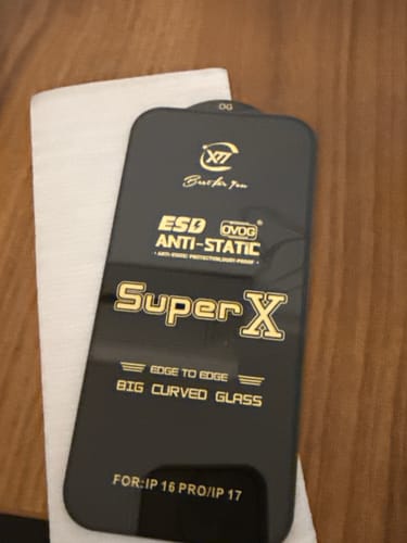 A reviewer shows the black packaging with gold text for the UltraShield Tempered Glass.