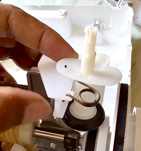 Close-up of a customer installing the white Bobbin Winder Assembly into a sewing machine.