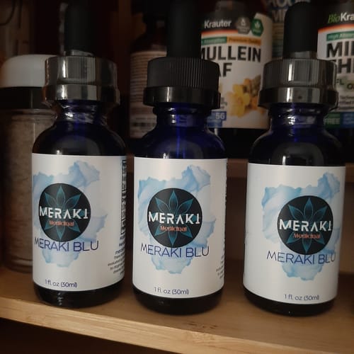 Customer's stock of three Meraki Blu dropper bottles arranged on a wooden shelf.
