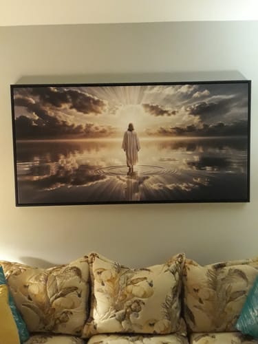 Customer's 'Walking on Water - Faith Wall Art' in a black frame, hung on a wall above their patterned sofa.
