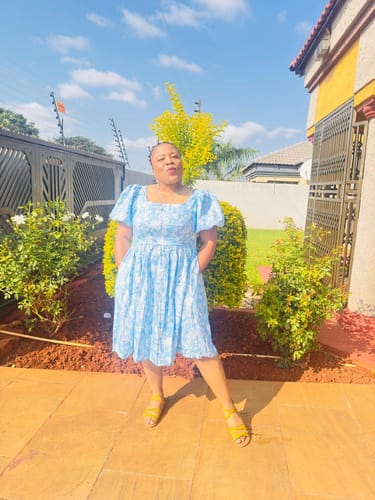 Reviewer standing outdoors in a light blue patterned Elegant Engagement Short Dress with puffy sleeves.