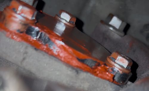 Close-up of a reviewer's EGR Delete Kit block-off plate, bolted and sealed onto an engine.