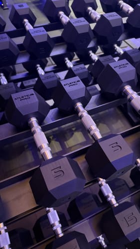 Rezensent zeigt eine Nahaufnahme der schwarzen Hexagon Hanteln PRO, die ordentlich auf einem Hantelständer gestapelt sind.