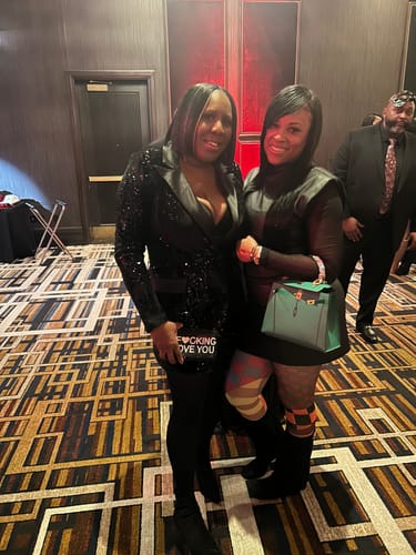 Customer holding the black IFLY Rhinestone Clutch with bold white text, paired with a black sequined blazer.