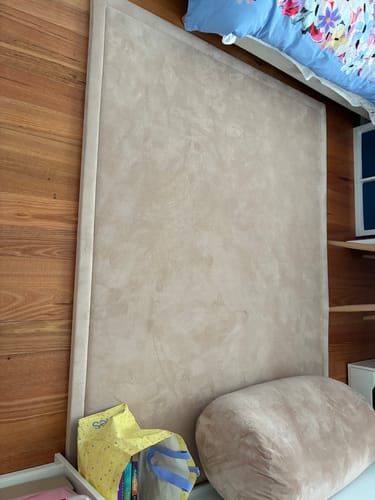 Customer's beige Mellow Mat leaning against a wooden floor in what appears to be a bedroom.