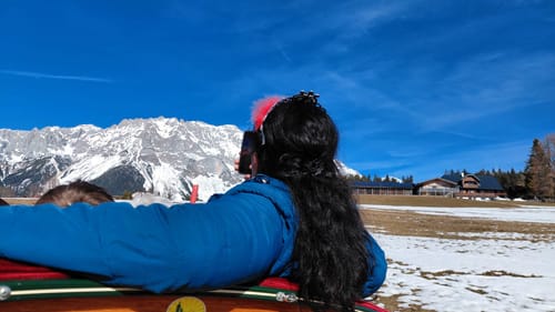 Rückansicht einer Kundin mit langen, dunklen Haaren vor einer verschneiten Berglandschaft, die das Ergebnis der Haarwäsche mit der Haarseife zeigt.