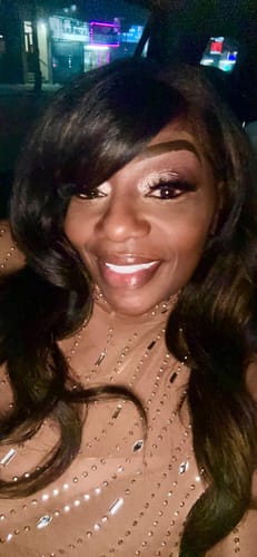 Close-up of a customer wearing the dark Outre Perfect Hairline wig styled with loose waves and a side bang.