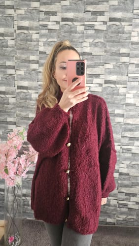 Kundin macht ein Spiegel-Selfie in der weinroten, übergroßen Bouclé-Strickjacke 'CozyGlam'.