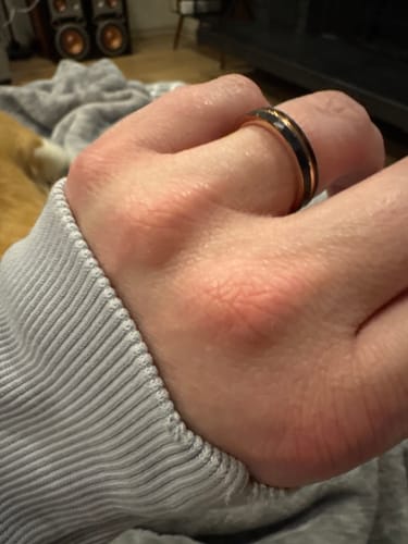 Close-up of a reviewer's hand wearing the black Apollo ring with a shiny rose gold inlay.