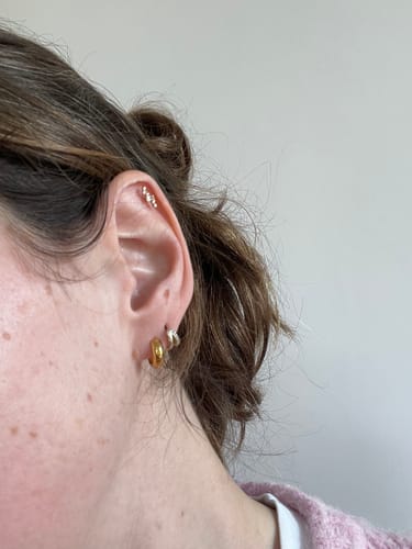Customer showing off the sparkling Aurora Flatback Stud with its constellation design in a cartilage piercing.