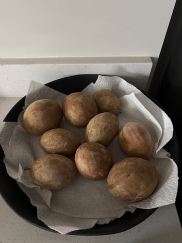 Customer's bowl of fresh, brown Sapodilla fruits resting on a paper towel.