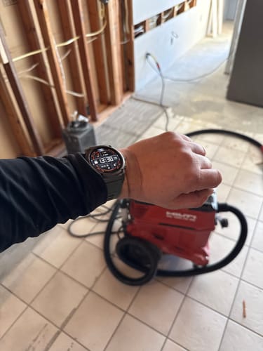 Customer's wrist wearing the Gard Pro Ultra 3 smartwatch with a dark band in a construction setting.
