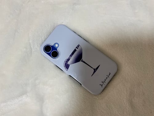 Reviewer's light purple 'sweet or sour' tough iPhone case with a cocktail glass graphic, resting on a soft white surface.