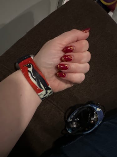 Customer's wrist showing the red 'Built for This' watch band with its prominent penguin graphic.