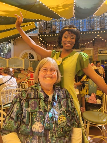 Reviewer wearing the Haunted Mansion “Haunted Houseguests” shirt while posing with a costumed character at a theme park.
