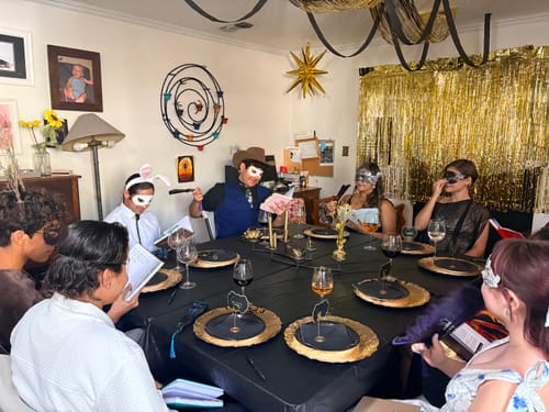 Customers play the Masquerade Murder Mystery game at a party, wearing fun masks and costumes around a decorated table.