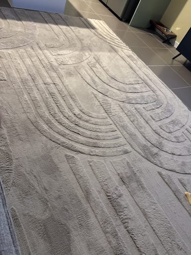 Customer's charcoal Mellow Mat showing its plush, carved 3D texture on a dark tiled floor.