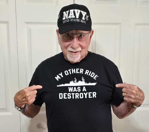 Customer wearing a Navy hat points proudly at his black 'My Other Ride Was A Destroyer' t-shirt.