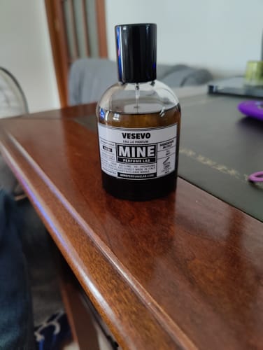 Recensore mostra il suo flacone di profumo Vesevo su un tavolo di legno.