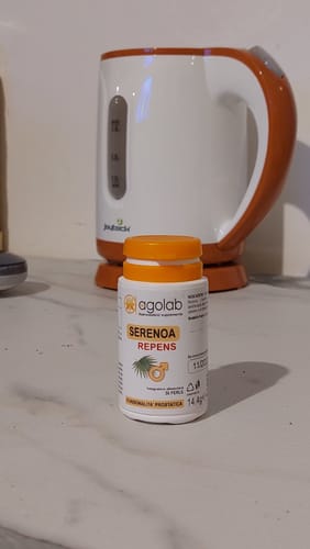 Il cliente mostra il flacone di integratori Serenoa Repens su un ripiano della cucina.