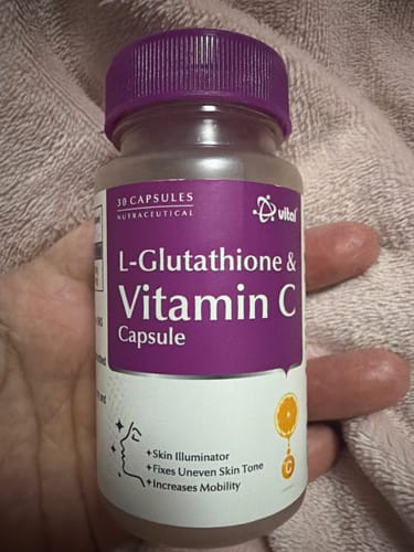 レビューアーがタオルを背景に手に持っているL-グルタチオン＆ビタミンCサプリのボトル。