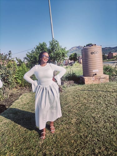 Customer smiling outdoors in the white Butterfly Hand Long Maxi Dress, showing its full skirt and flared sleeves.