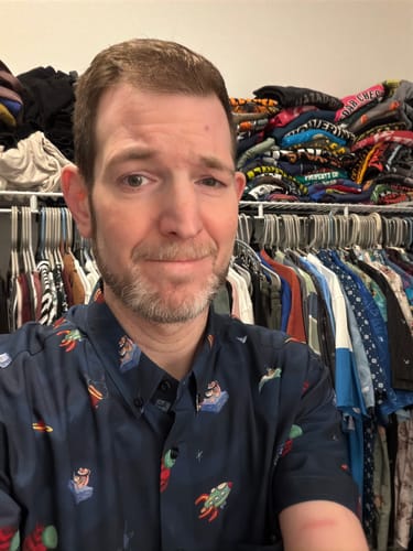 Customer wearing the patterned Ren & Stimpy "Space Madness" short sleeve shirt in a closet.