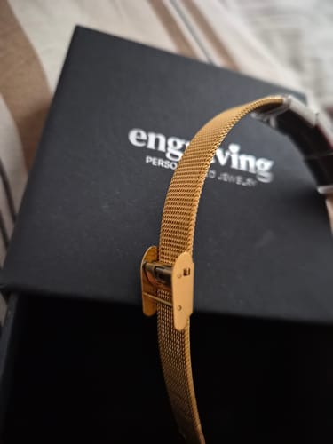 Close-up of the reviewer's gold Lux bracelet, showing the adjustable clasp and mesh band.