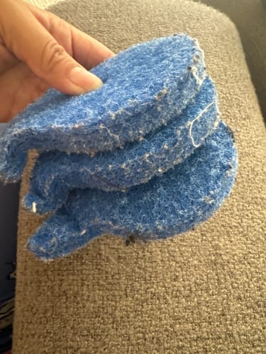 Customer holding a stack of three blue Laundry Pet Hair Removal Fish covered with collected lint and hair.