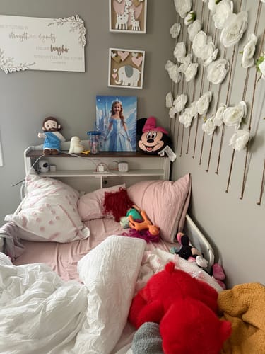 Customer's The Ice Princess portrait displayed on a shelf at the head of a child's bed, surrounded by toys.